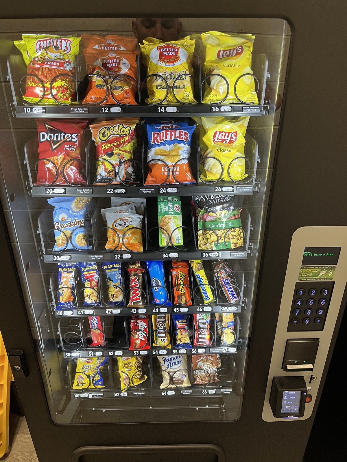 Fully stocked Valiant Vending snack machine with chips, candy, and cookies